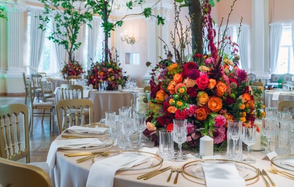 Wedding table decoration. Beautiful bouquet of flowers on the table, next to plates, crystal glasses and plates